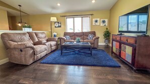 A living room with a brown leather sofa, a glass coffee table, and a television on a cabinet. - Spacious/Clean 4 Bedroom 2 Bathroom Home away from Home. (Mandan)