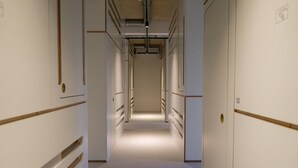 A narrow, well-lit hallway with doors on both sides, leading to individual rooms. - soom Salzburg I Capsule Hotel (Salzburg)