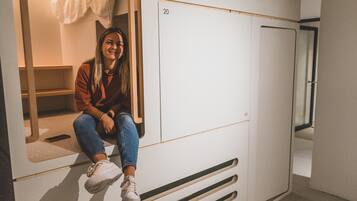 En person sidder på en hvid garderobe med skuffer nummereret 19 og 20.