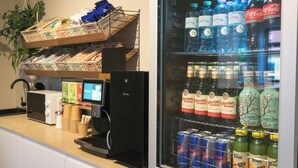A kitchen area with a refrigerator stocked with beverages, a coffee machine, and a microwave. - soom Salzburg I Capsule Hotel (Salzburg)