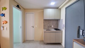 A compact kitchen with a built-in stove, a sink, and a microwave. There are cabinets above and below the countertop. - Mar de Campas (Tamandaré)