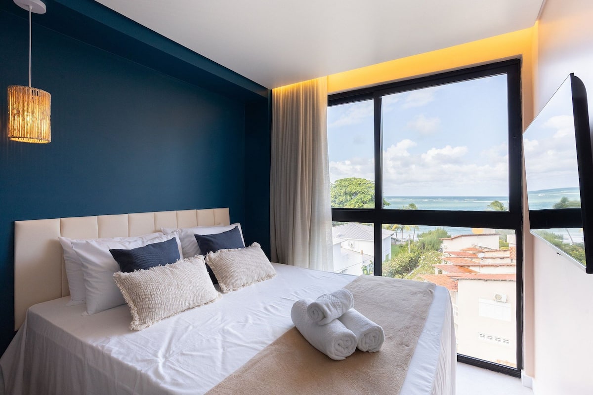 Ein Hotelzimmer mit einem großen Bett, Blick auf die Stadt und einer Hängelampe.