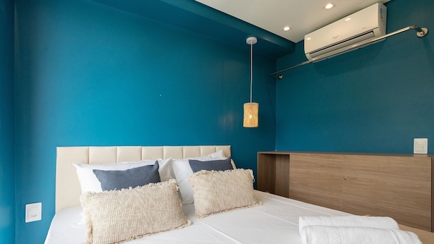 A bedroom with a bed, pillows, a hanging light fixture, and an air conditioning unit. - Mar de Campas (Tamandaré)