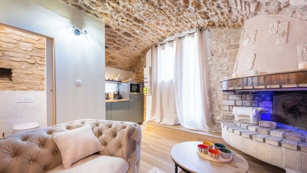 Ein gemütliches Wohnzimmer mit Stein Decke, Kamin, einer Couch und einem Esstisch mit bunten Schalen.