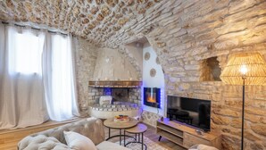 Ein gemütliches Wohnzimmer mit Kamin aus Stein, einem Fernseher und bequemen Sitzgelegenheiten.