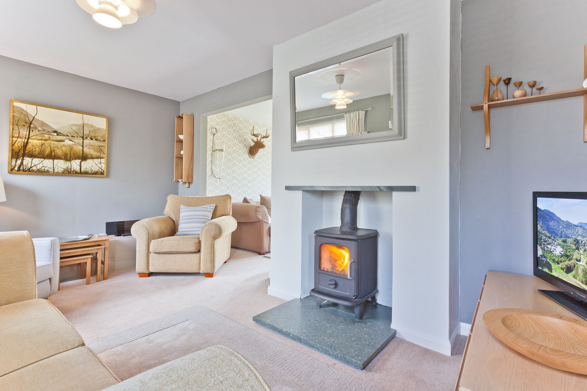 A cozy living room with a fireplace, comfortable seating, a television, and a decorative mirror.