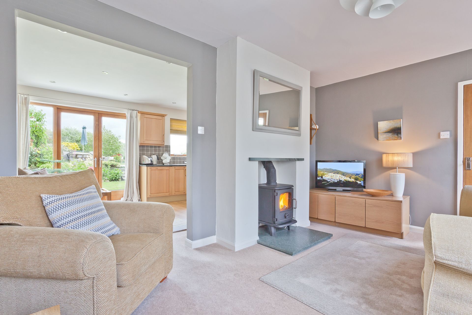 A modern living room with a fireplace, a television, and a view of the garden.