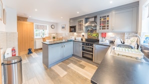 A modern kitchen with grey cabinets, a central island, a built-in oven, and a stainless steel sink.