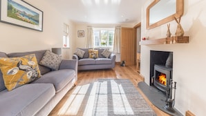A cozy living room with a fireplace, a sofa set, and a large window.