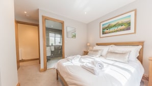 A bedroom with a large bed, a wooden headboard, and a painting of a landscape.