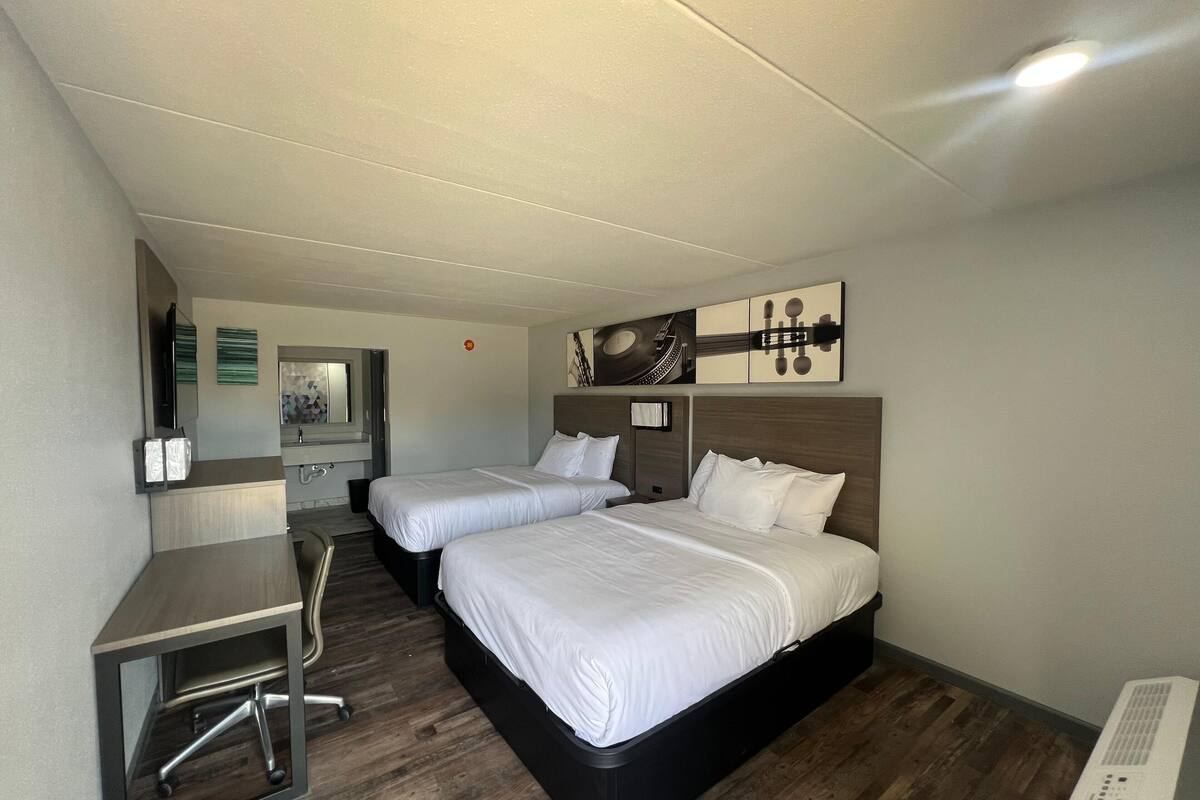 A hotel room with two beds, a desk, and a chair.