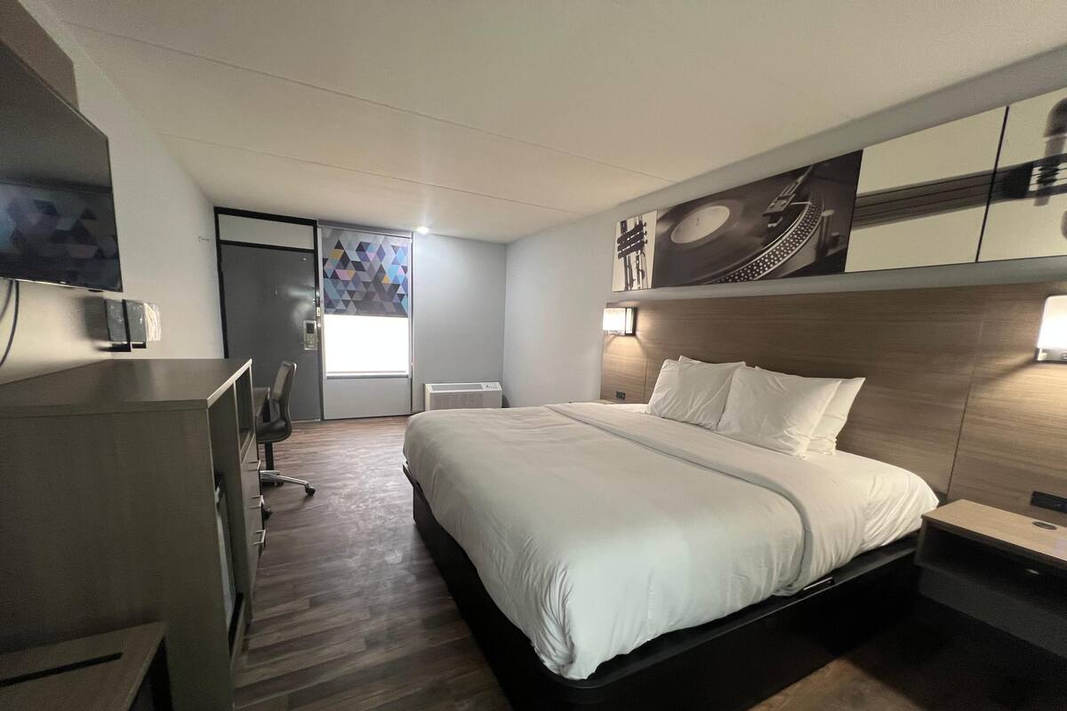 A modern hotel room with a large bed, a desk, and a chair.