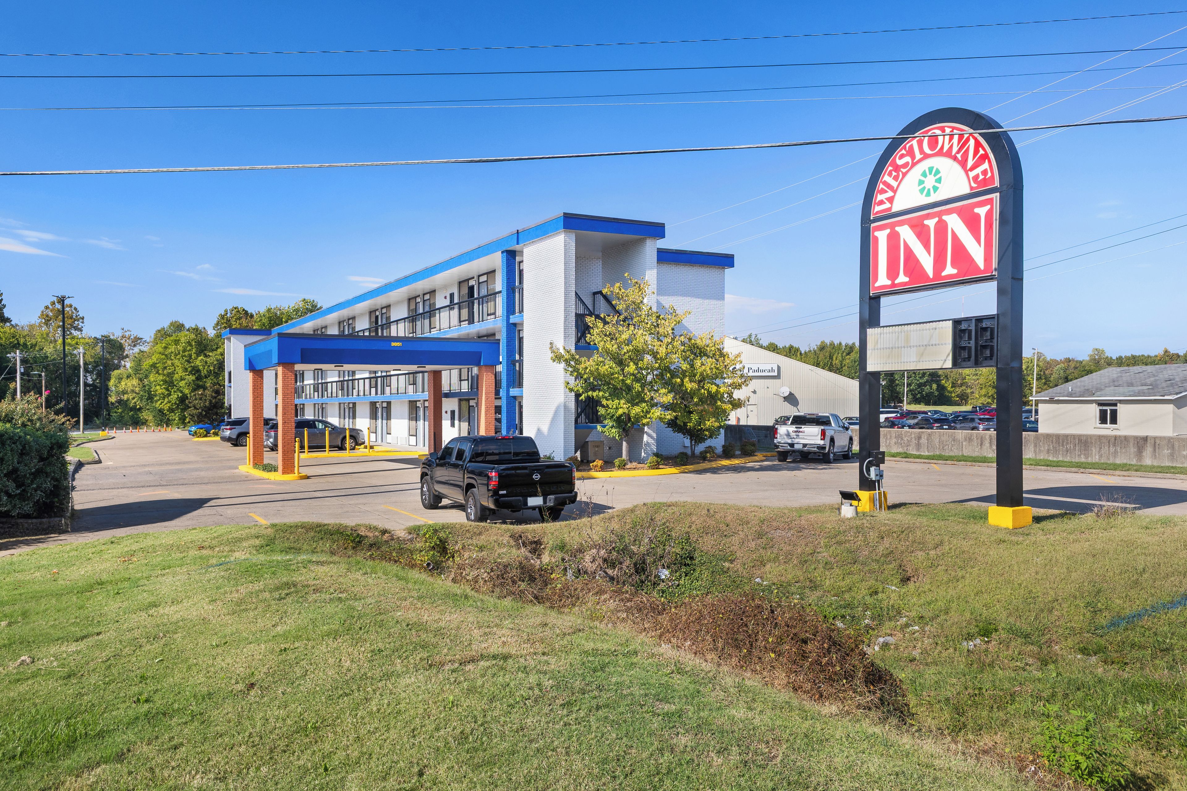 A building with a sign that reads 'Inn' and a parking lot with a few vehicles.