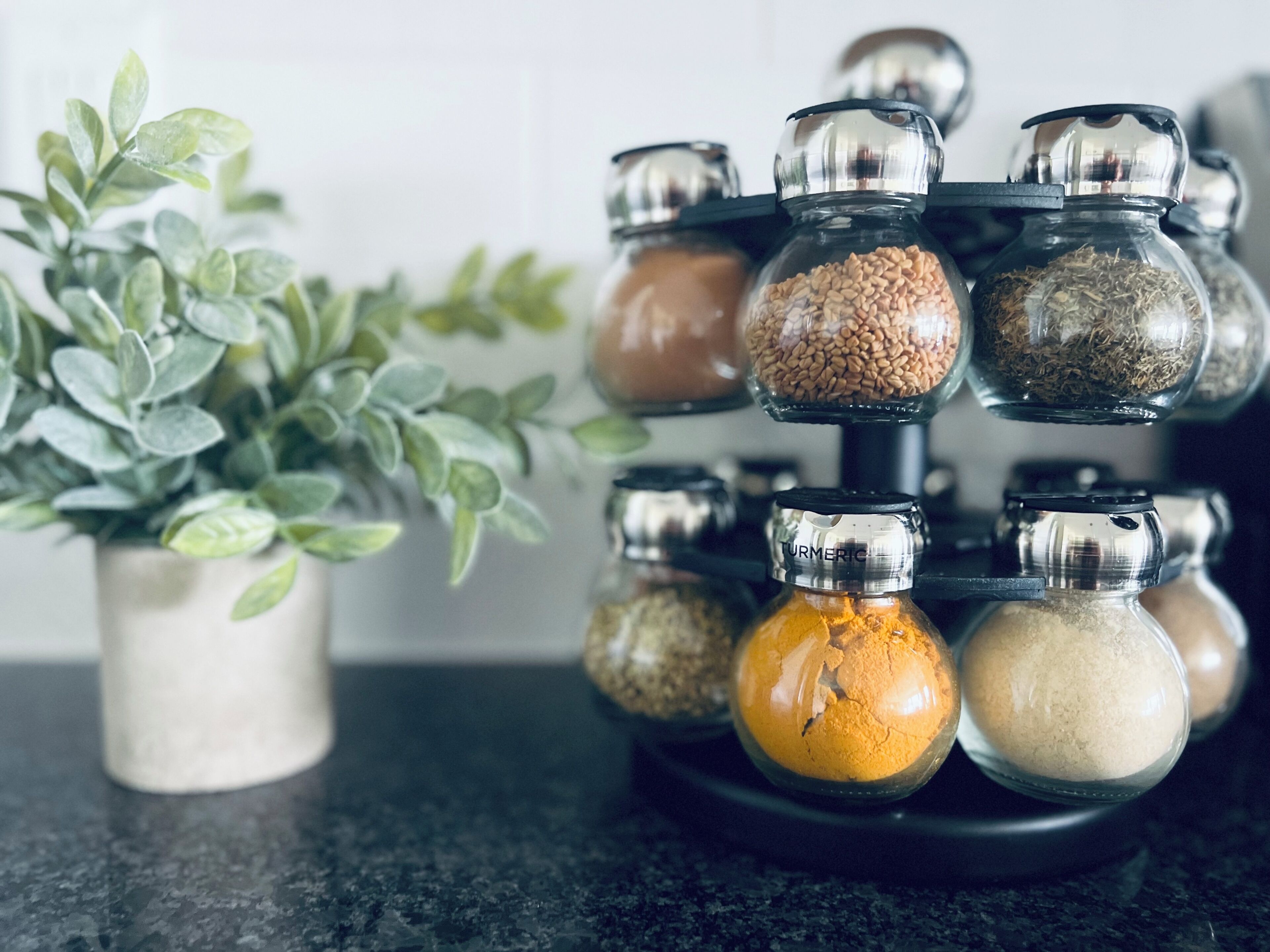 Un étagère à épices contenant plusieurs récipients en verre remplis de différentes épices.