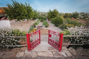 Un sendero en un jardín que lleva a una puerta con una cerca rústica.