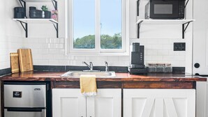 A modern kitchen with white cabinets, a stainless steel refrigerator, a coffee maker, and potted plants on shelves. - Exuma Studio w/ King Bed • Ideal for Couples or Solo Travel • Near George Town (George Town)