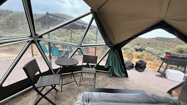 A tented room with a bed, a table, and chairs. - Dome 4 Glamping at Bear Lake (Laketown)
