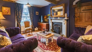 Ein Wohnzimmer mit violetten Sofas, einem Kamin, einem hölzernen Kaminvorsatz und einem großen Spiegel.