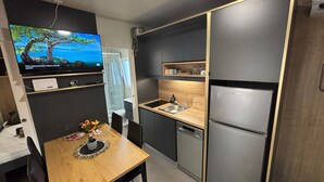 Una cucina compatta con tavolo da pranzo in legno, lavello incassato e frigorifero in acciaio inossidabile.