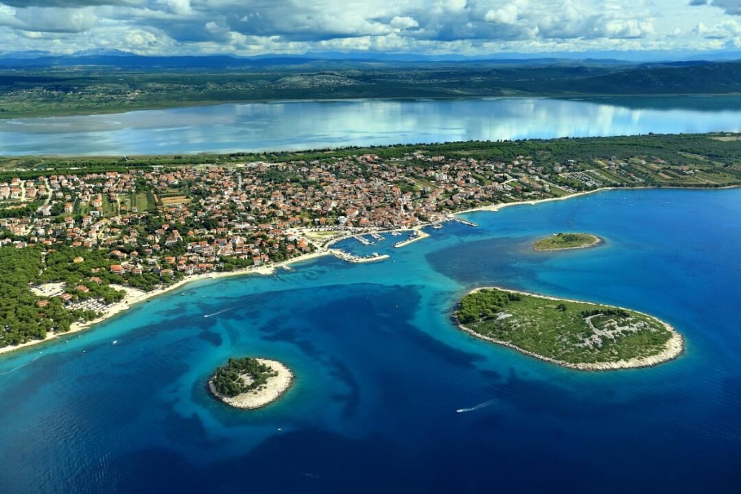 An aerial view of a coastal town with a marina, clear blue waters, and several small islands.