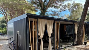 Una zona relax esterna moderna con struttura in metallo, tende e una bicicletta nelle vicinanze.