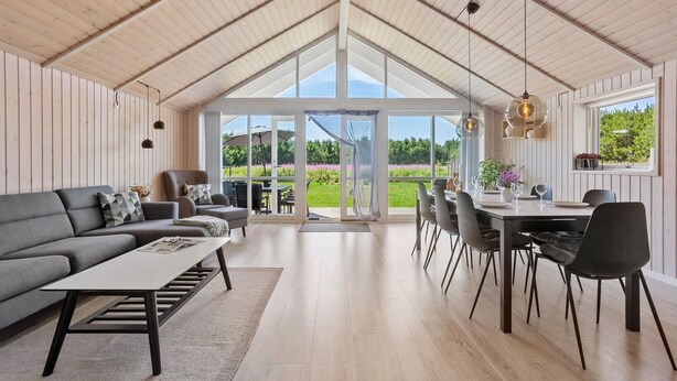 A spacious living area with a high ceiling, a dining table, and a sofa. - Nice home in Jerup with sauna (Jerup)