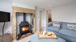 A cozy living room with a stone fireplace, a blue sofa, and a tray with breakfast items. - Paddock View -  a cottage that sleeps 8 guests  in 4 bedrooms (Osmotherley)