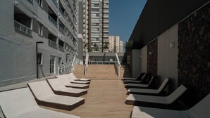 Un área de descanso en la azotea con tumbonas y una escalera que sube a un piso superior.
