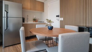 Una cocina moderna con un refrigerador de acero inoxidable, una mesa de comedor con cuatro sillas y una planta en maceta sobre la mesa.