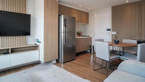 Una cocina moderna con refrigerador empotrado, muebles de madera y un comedor con mesa y sillas.
