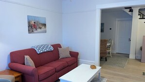 Una sala de estar con un sofá rojo, una mesa de centro blanca y un cuadro en la pared.