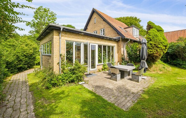 A two-story house with a brick exterior, large glass windows, and a patio with outdoor furniture. - 3 bedroom lovely home in Nykøbing M (Nykøbing M)