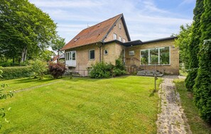 A two-story house with a sloped roof, a front porch, and a well-maintained lawn. - 3 bedroom lovely home in Nykøbing M (Nykøbing M)