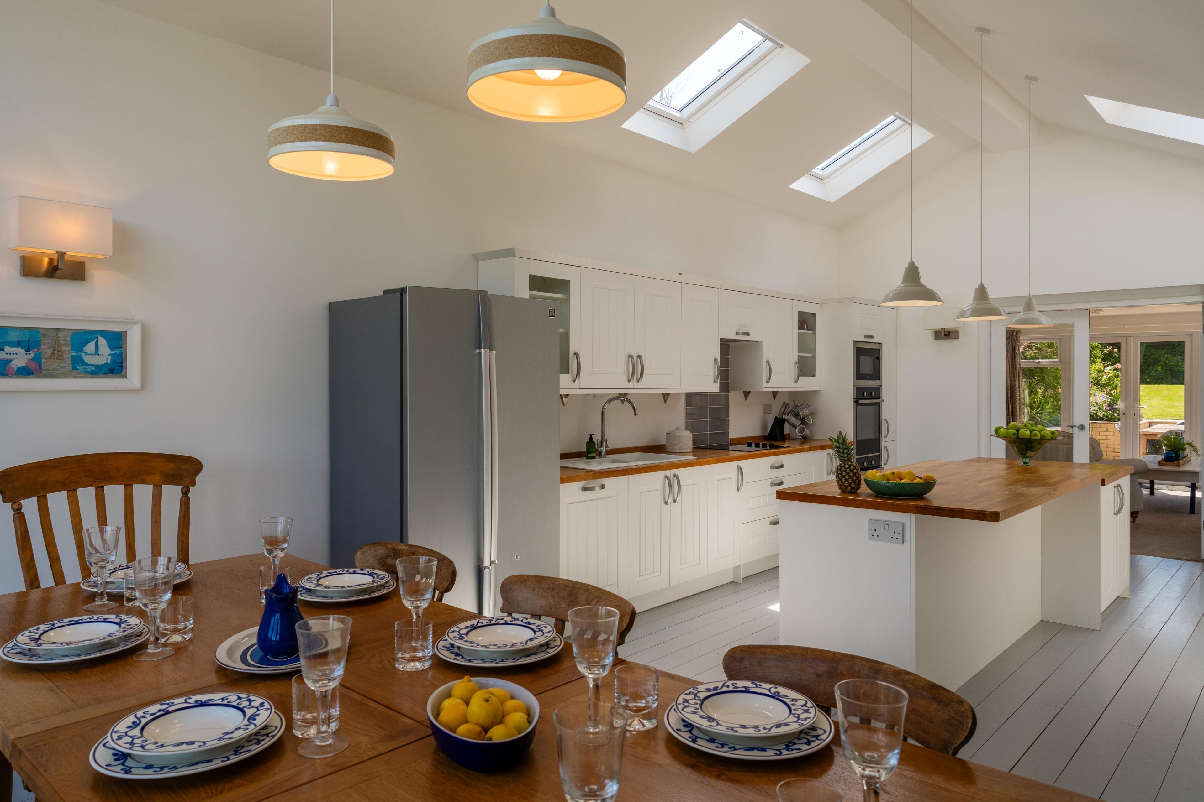 A modern kitchen with white cabinets, a central island, and a dining area with a wooden table set for six.