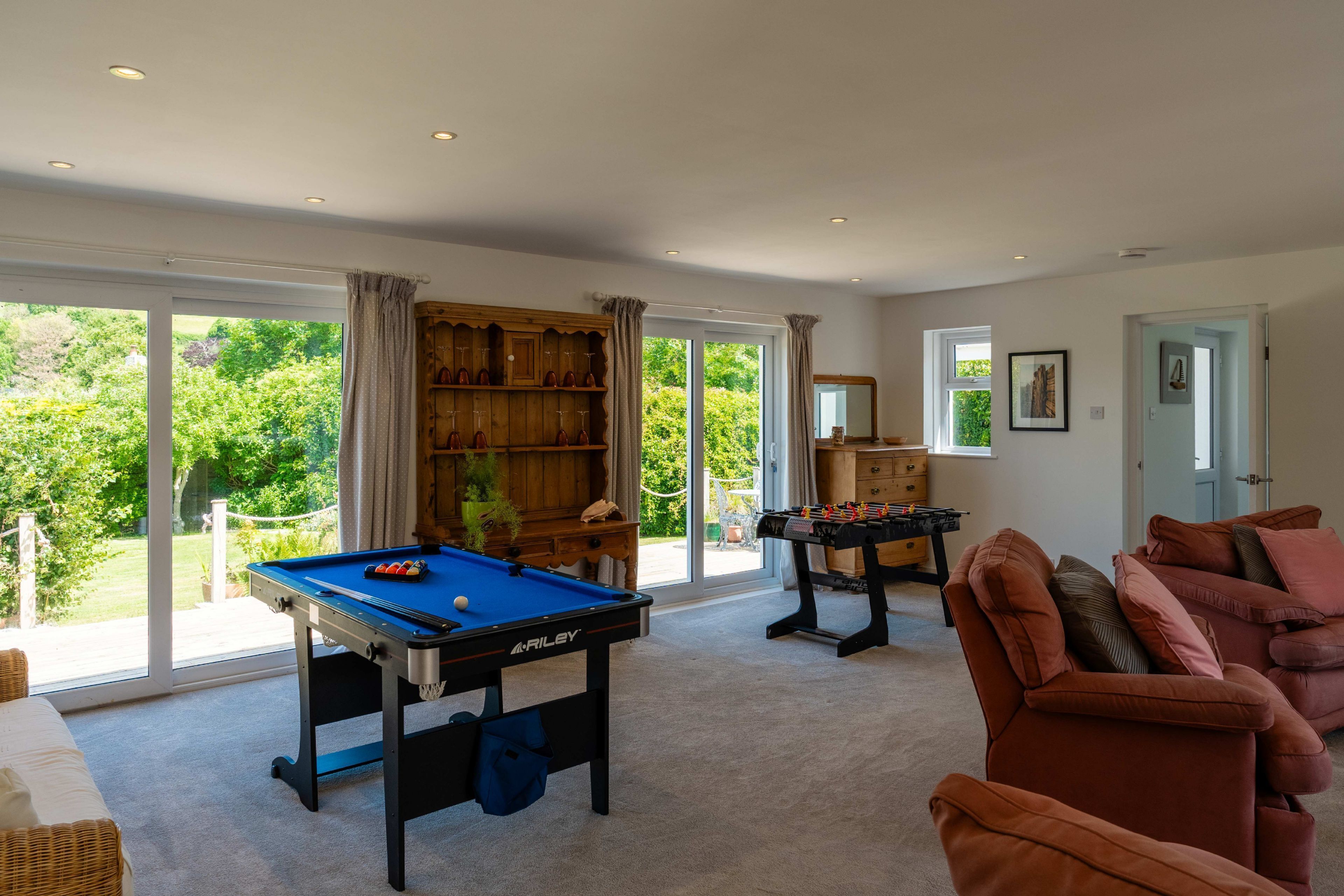Une pièce spacieuse équipée d’une table de billard, d’un baby-foot et d’un coin salon confortable.