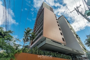 Un edificio de gran altura con varios balcones, un cartel que indica '60 UNICO' y la marca 'sedzone'.