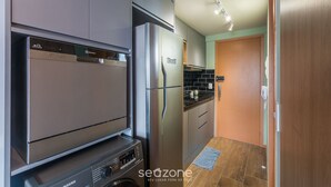Une cuisine compacte dotée d’appareils électroménagers modernes, d’un lave-linge et d’une porte en bois.