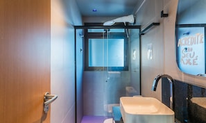 Un baño moderno con cabina de ducha de vidrio, un lavamanos blanco y un espejo con un letrero.