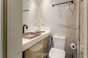 Casa de banho moderna com painel de parede em mármore, lavatório com espelho e sanita.