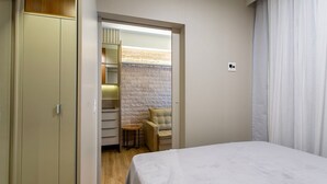 A bedroom with a bed, a chair, a wardrobe, and a small table.