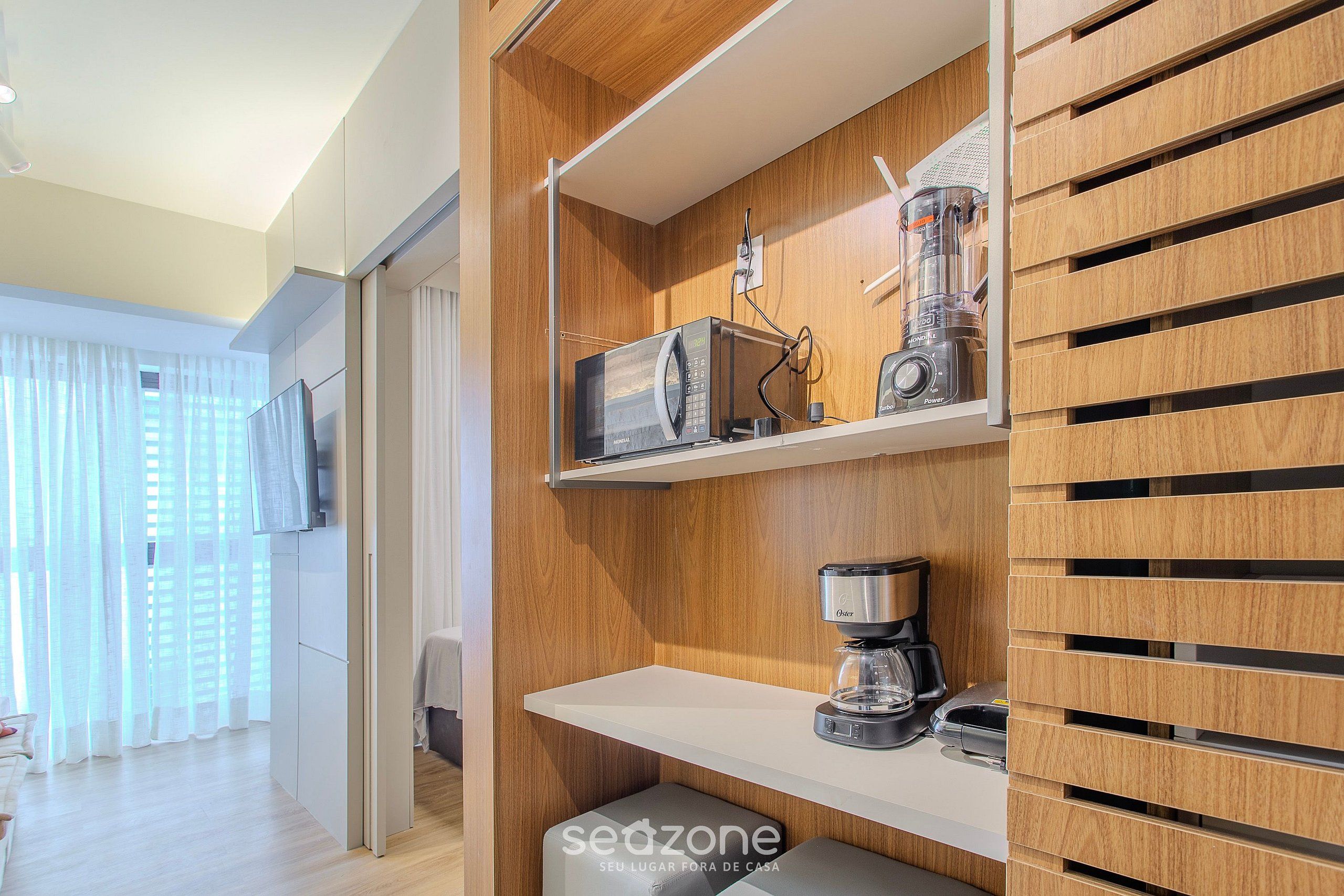 A modern kitchen with built-in appliances, including a microwave, coffee maker, and blender, and a wooden panel design.
