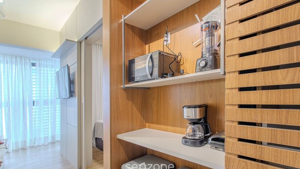 A modern kitchen with built-in appliances, including a microwave, coffee maker, and blender, and a wooden panel design.