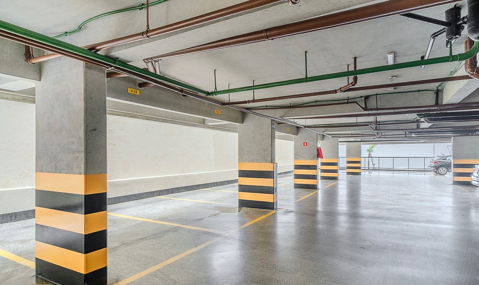 Un estacionamiento vacío con pilares de hormigón y barreras a rayas amarillas y negras.