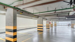 An empty parking garage with concrete pillars and yellow and black striped barriers.