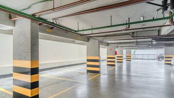 An empty parking garage with concrete pillars and yellow and black striped barriers.