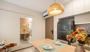 A modern kitchen with a large refrigerator, a dining table set for two, and a hanging light fixture.