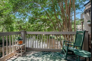 A balcony with a wooden railing, a green chair, and a small table with a potted plant. - 2402 Lighthouse Tennis at The Sea Pines Resort (Hilton Head Island)