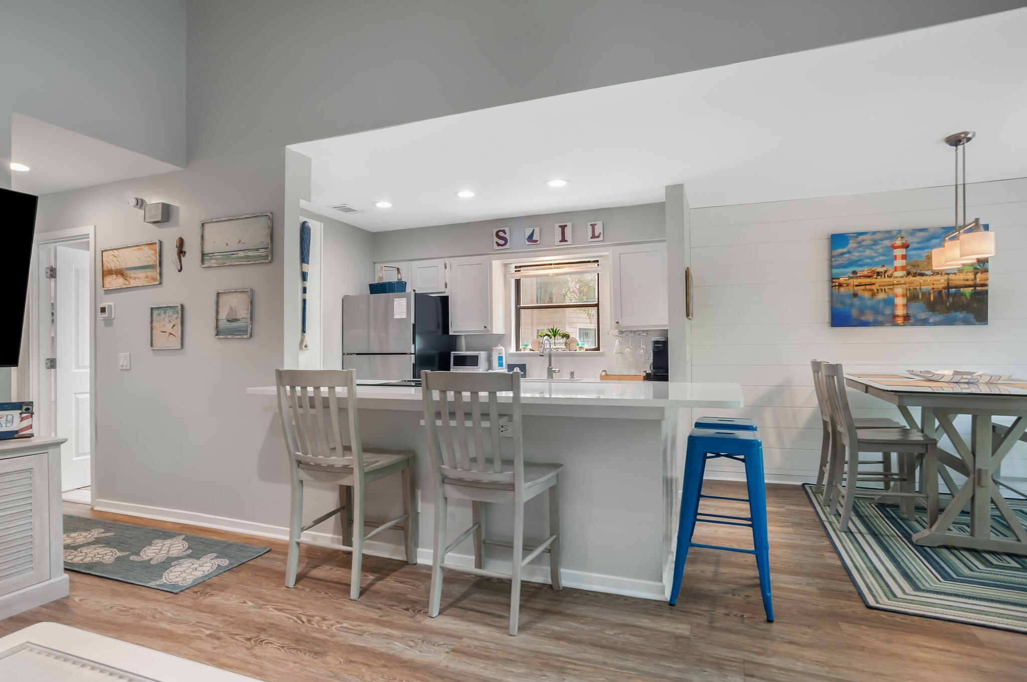 A modern kitchen with a bar area, white cabinetry, and a dining table with chairs.