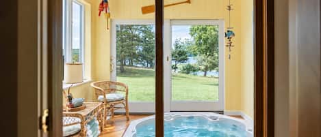 Sunroom with an open private hot tub overlooking the lawn
