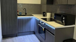 Una cocina moderna con gabinetes oscuros, un lavamanos de acero inoxidable, un microondas negro y un horno empotrado.